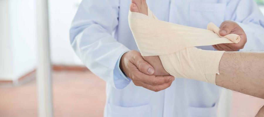 Unrecognizable doctor bandaging foot of patient